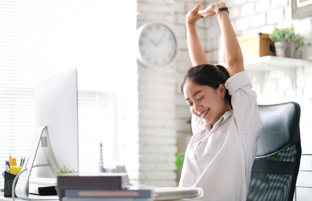 Girl happily stretching at desk