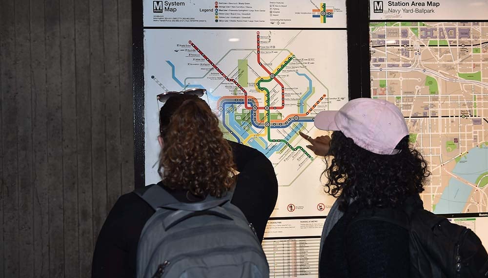 Two women using a Metro station map